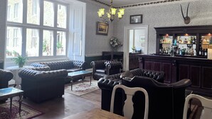 A bar area with a wooden counter and various bottles. There are leather sofas and a glass coffee table. - Grafton Manor (Bromsgrove)