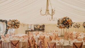 A tented event space with round tables, chairs, and floral centerpieces. - Grafton Manor (Bromsgrove)