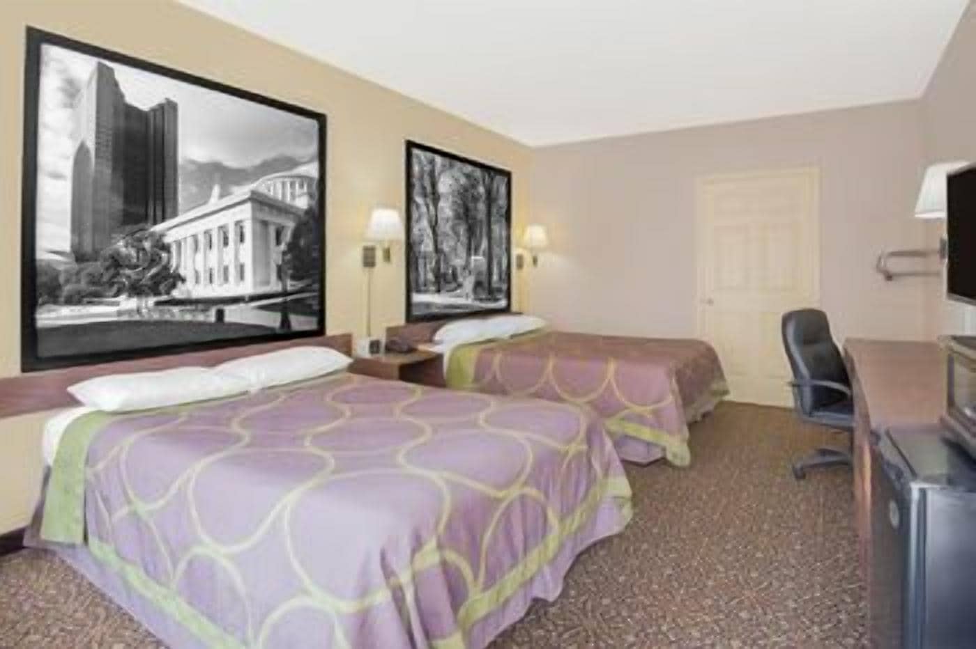 Ein Hotelzimmer mit zwei Betten, einem Schreibtisch, einem Stuhl und einem Fernseher.