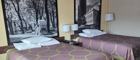 Habitación de hotel con dos camas, alfombra estampada y dos fotografías grandes en blanco y negro en las paredes.