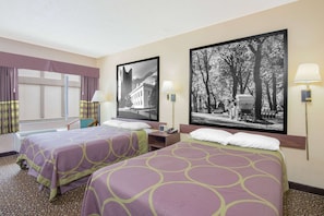 A hotel room with two beds, a window with curtains, a chair, and two wall-mounted lamps. - Ashland Inn & Suites (Ashland)