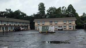 A parking lot with a motel building in the background. - Ashland Inn & Suites (Ashland)
