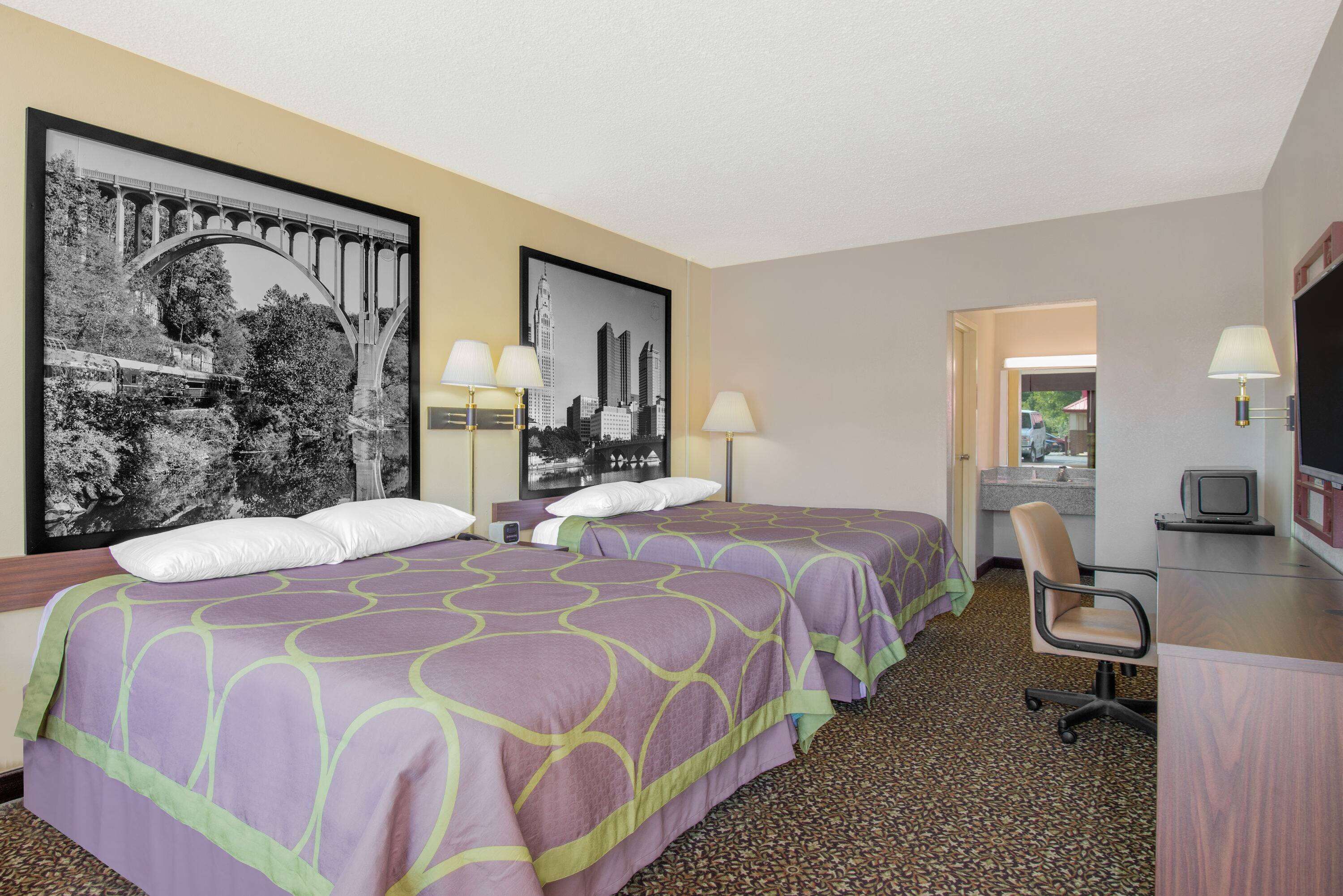 A hotel room with two beds, a desk with a computer, and a TV.