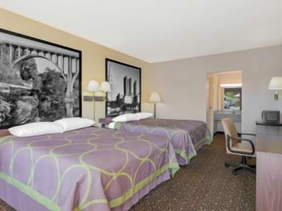 Habitación de hotel con dos camas, un escritorio, una silla y un televisor.