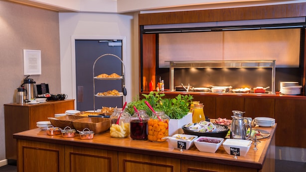 Un bufé con diversos alimentos y bebidas, una estación de café y una barra de ensaladas.