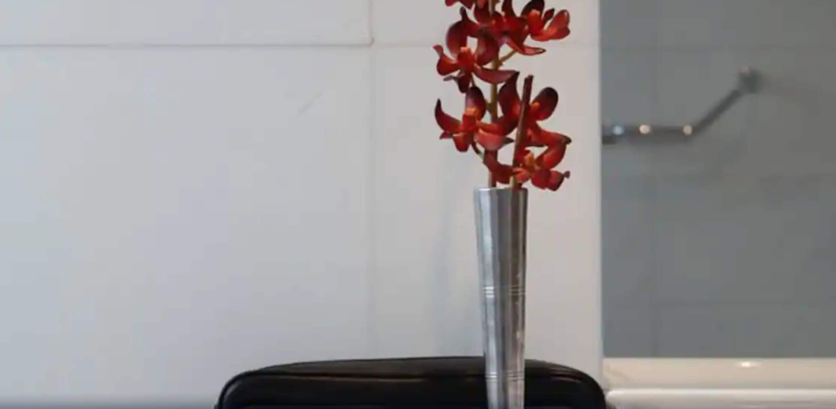 A vase with red flowers on a black chair.
