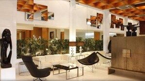 Un hall d’entrée spacieux, doté de mobilier moderne, d’une grande sculpture et d’un espace central aménagé en jardin intérieur.