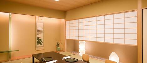 Una sala de reuniones tradicional japonesa con suelo de tatami, una mesa baja y puertas correderas shoji.