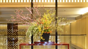 Un'ampia composizione floreale su un tavolo, una scala sullo sfondo e un design d'interni moderno.