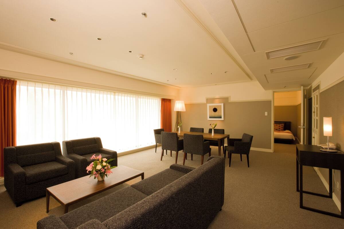 Hotellihuone, jossa on oleskelutila, ruokapöytä ja sänky.