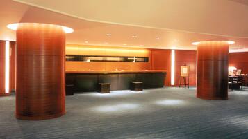 A spacious lobby with a modern design, featuring large wooden columns, a reception desk, and a seating area.