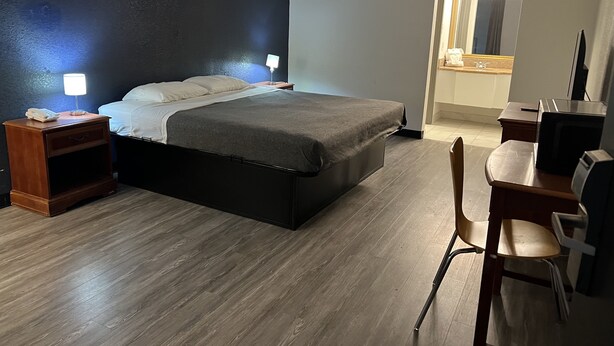 A hotel room with a bed, bedside tables, a desk, and a chair. - The Nest Hotel Suffolk (Suffolk)
