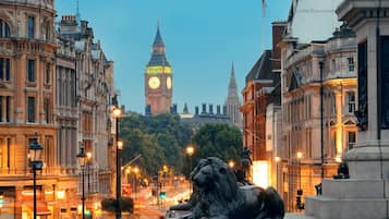A historic building with ornate architecture, a prominent clock tower, and a lion statue in the foreground.