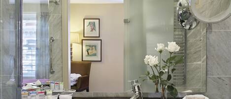 A modern bathroom with a large mirror, a sink, and toiletries.