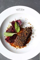 Une assiette de nourriture comprenant un morceau de viande, des betteraves et des légumes verts.
