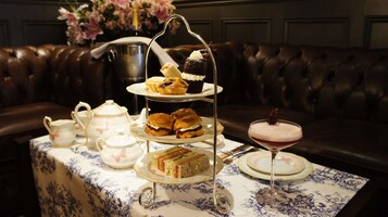 A tiered dessert stand with various pastries and a martini glass on a table with a floral tablecloth.