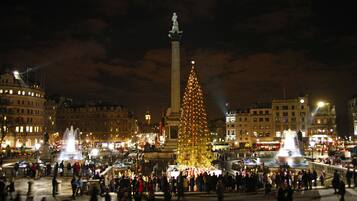 Une place publique avec un grand sapin de Noël illuminé et un monument central.