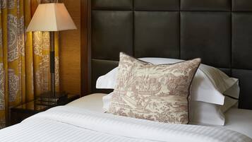 A neatly made bed with a patterned pillow, a bedside lamp, and curtains with a traditional design.