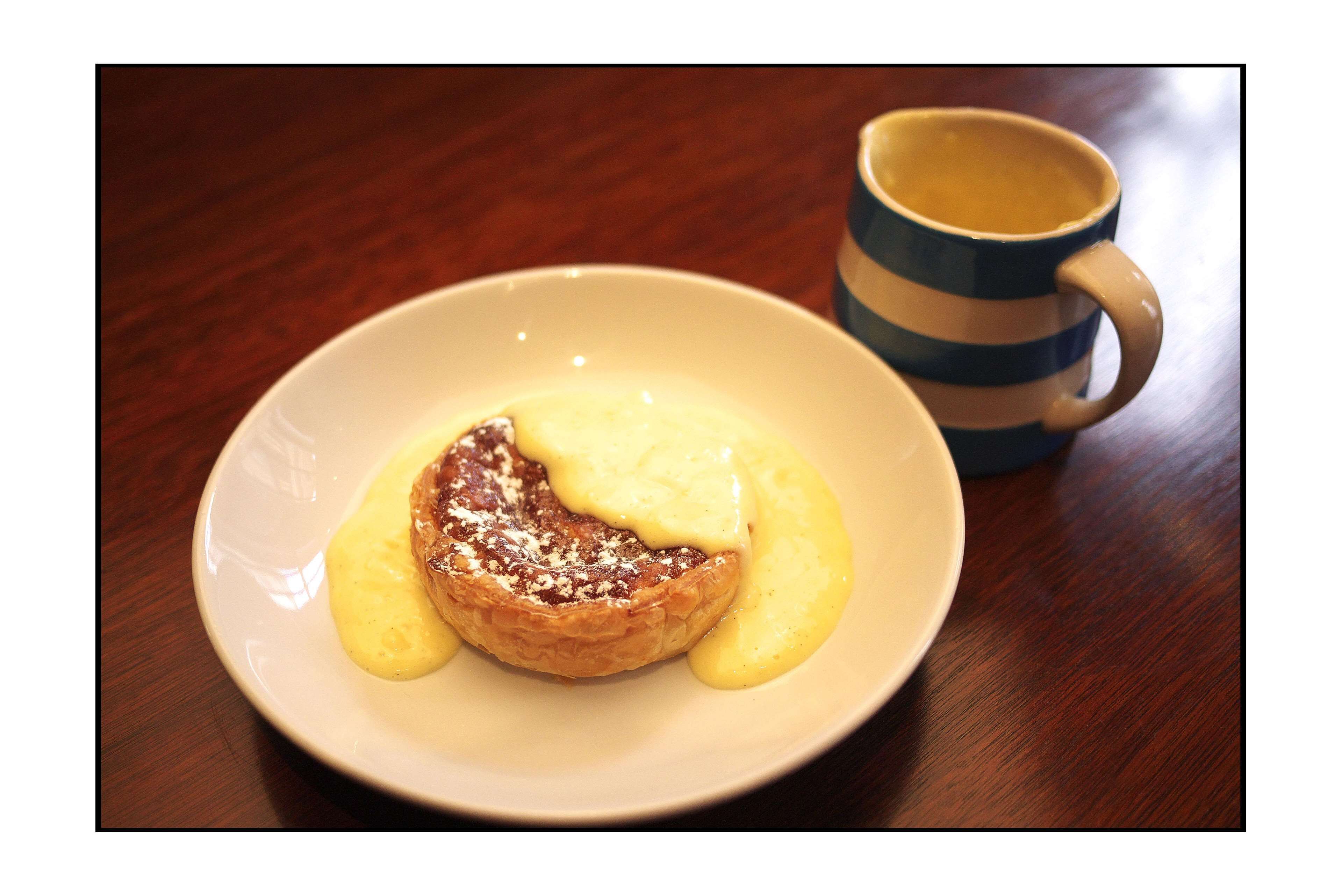 Un plato con un pastel y una taza sobre una mesa de madera.