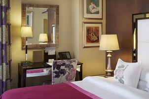 Ein Hotelzimmer mit einem Bett, einem Schreibtisch mit Telefon, einem Stuhl und einer Lampe.
