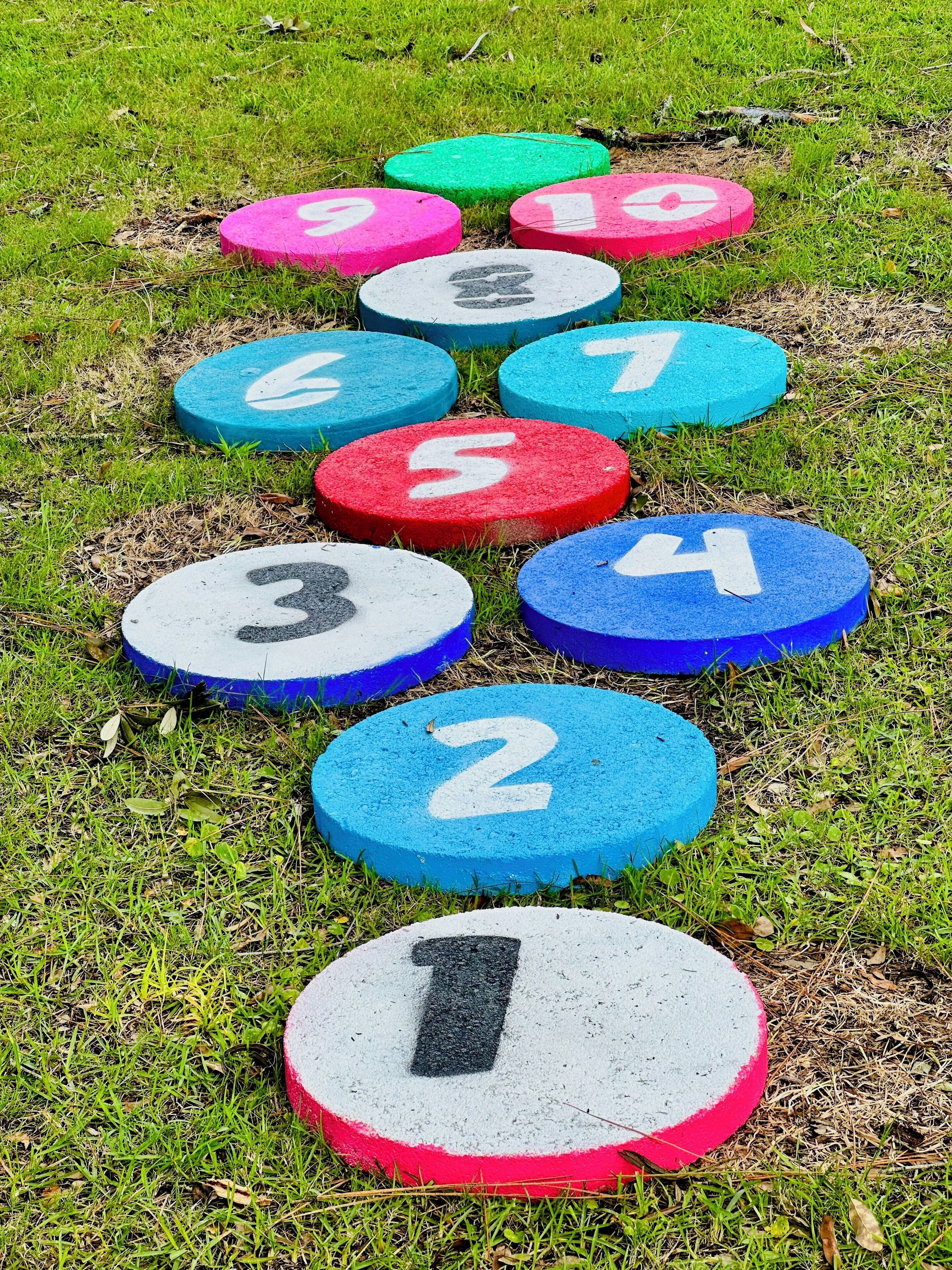 A series of numbered stepping stones on a grassy field.