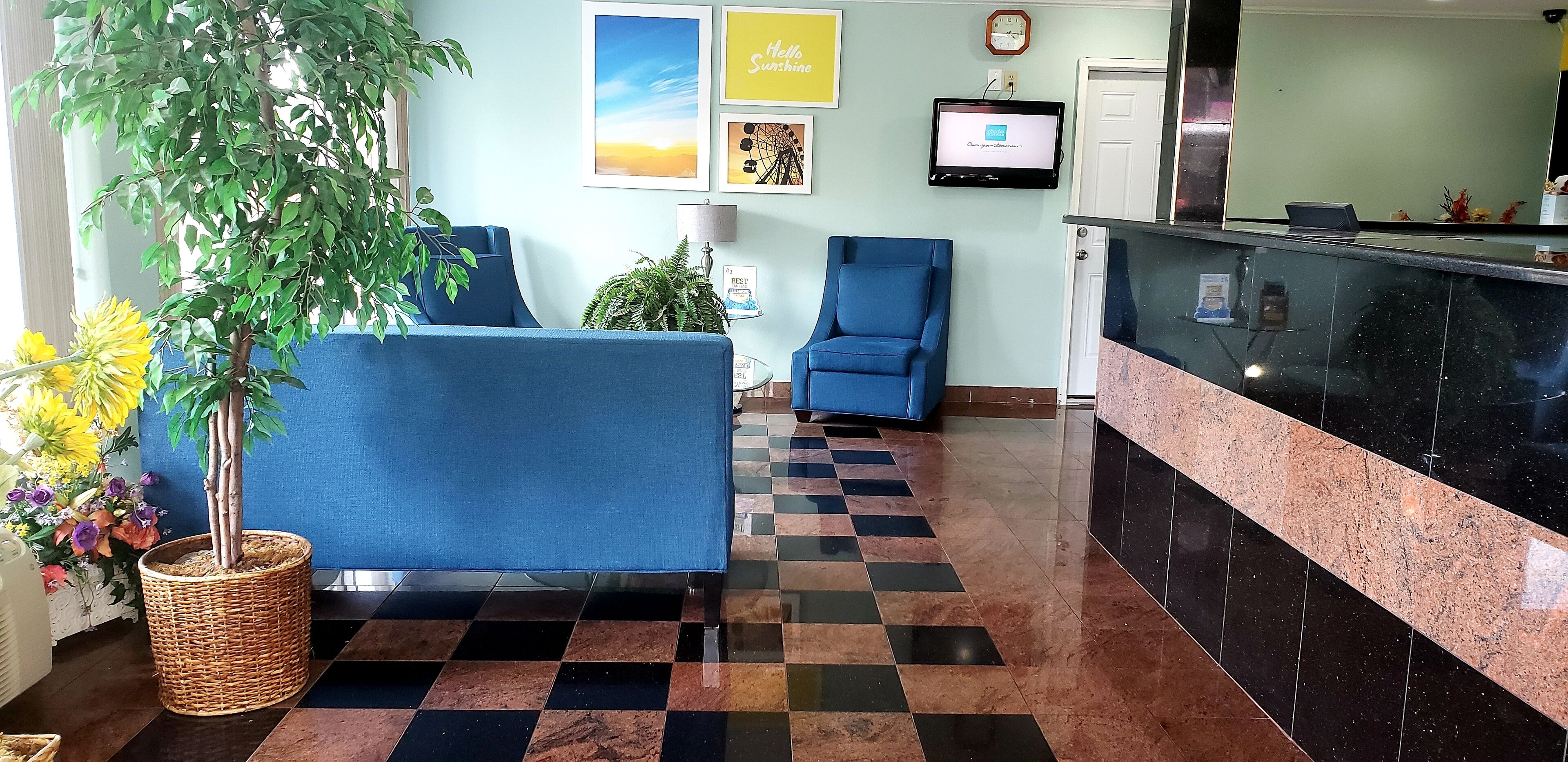 A reception area with a checkered floor, a reception desk, a blue armchair, and a potted plant.