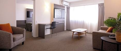 A modern living room with a sofa, a dining table, and a kitchen area with a TV.