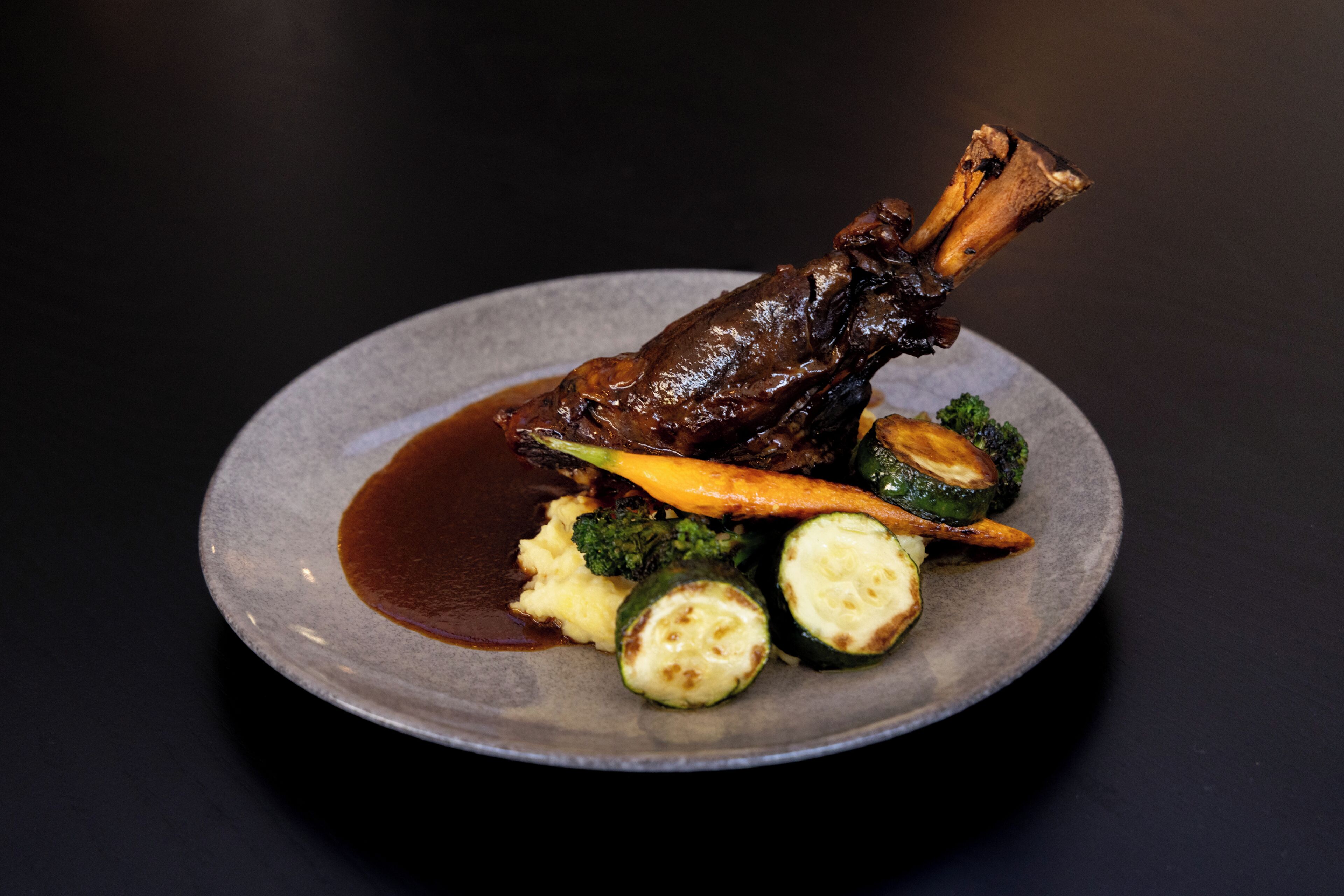 A plate with a roasted meat, mashed potatoes, and vegetables.