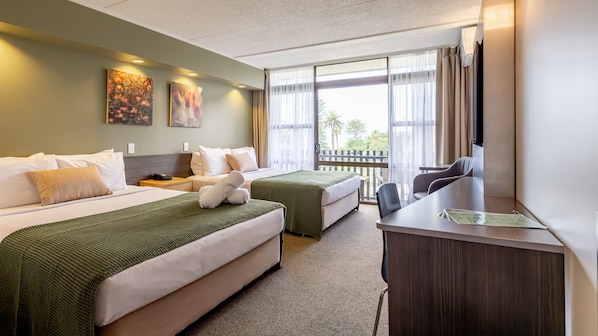 A hotel room with two beds, a desk, and a balcony with a view. - Auckland Rose Park Hotel (Auckland)