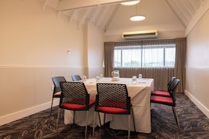 Uma sala de conferências com uma mesa, cadeiras e um aparelho de ar condicionado.