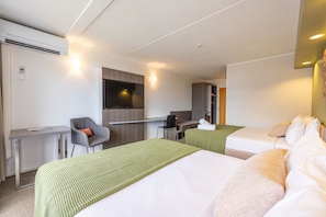 A hotel room with two beds, a desk, a chair, a flat-screen TV, and a wardrobe. - Auckland Rose Park Hotel (Auckland)