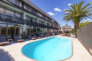 A swimming pool with lounge chairs and a palm tree.