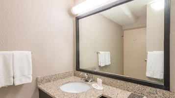 Un bany amb un lavabo de superfície de granit, un mirall i dues tovalloles blanques penjades a la paret.