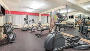 Ein Fitnessstudio mit Laufbändern, Crosstrainern und Gewichtsbänken.