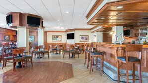 Ein großzügiger Barbereich mit Holzkörpern und gefliestem Boden, der eine Bar und verschiedene Sitzgelegenheiten bietet.