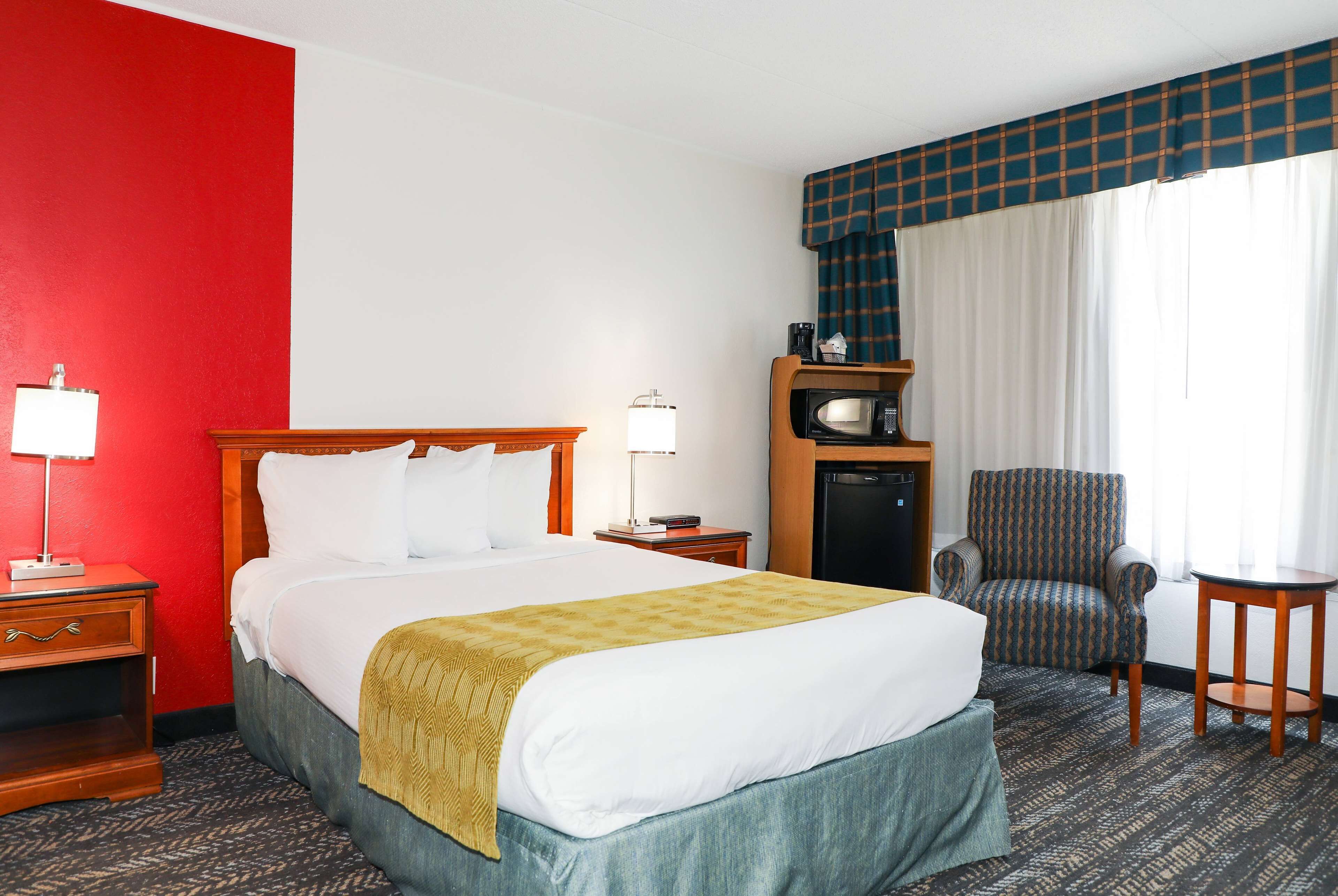 Een hotelkamer met een bed, een stoel, een magnetron en een nachtkastje.
