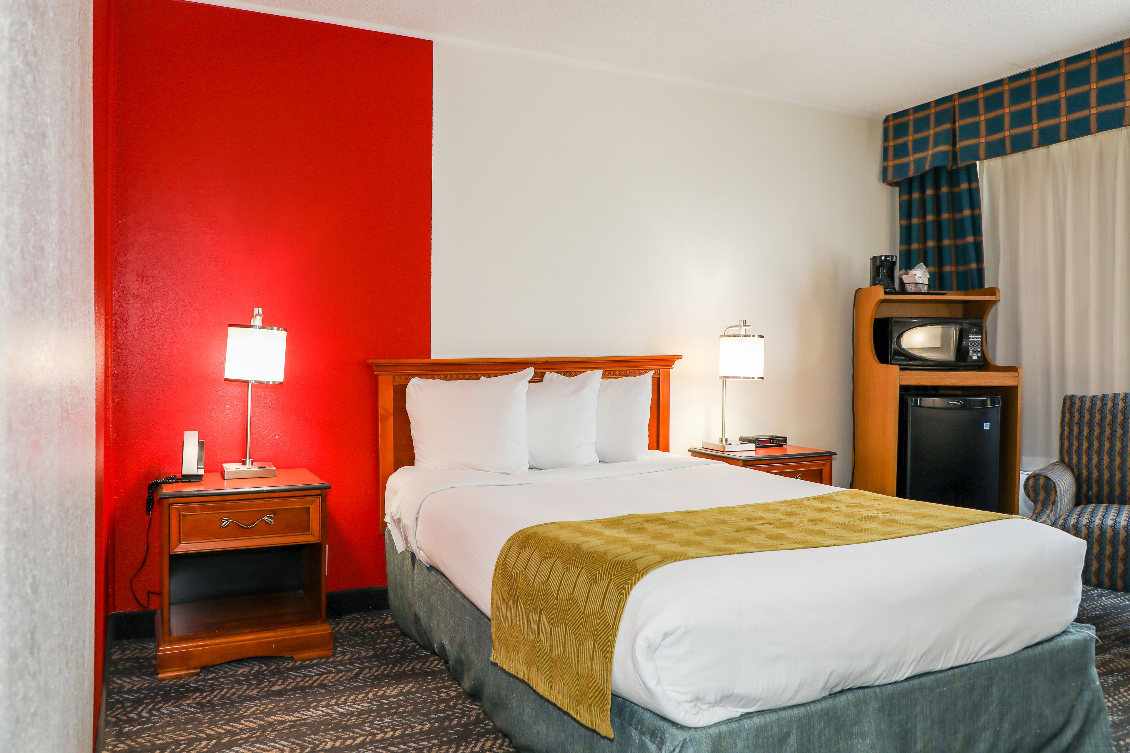 Ein Hotelzimmer mit Bett, Nachttisch, Lampe, Fernseher und Stuhl.