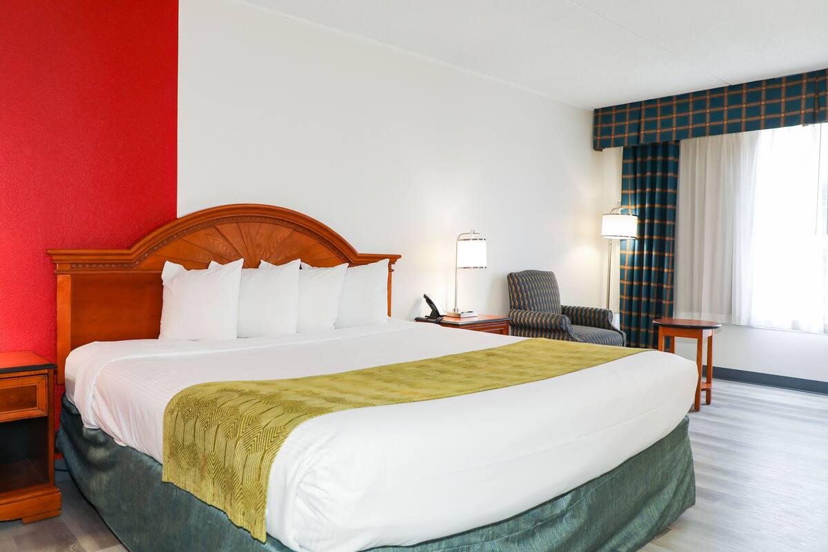 Una habitación de hotel con una cama grande, una silla, un escritorio y una lámpara.