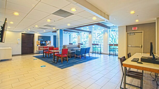 A modern hotel lobby with a reception desk, seating area, and a view of the outdoors.