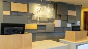 A hotel reception desk with a modern design, a digital display, and a sign for 'Holiday Inn Express.' - Holiday Inn Express Anaheim West by IHG (Anaheim)