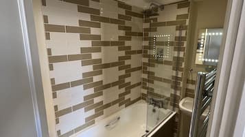 Un baño moderno con ducha envuelta en vidrio, bañera independiente y tocador con espejo.