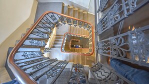 Una escalera de caracol con barandillas de metal decoradas y un espejo central que refleja las escaleras.