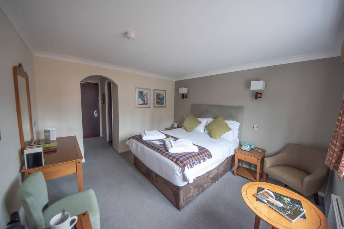 A hotel room with a bed, a chair, a small table, and a desk.