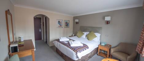 Una habitación de hotel con una cama, una silla, una mesita y un escritorio.