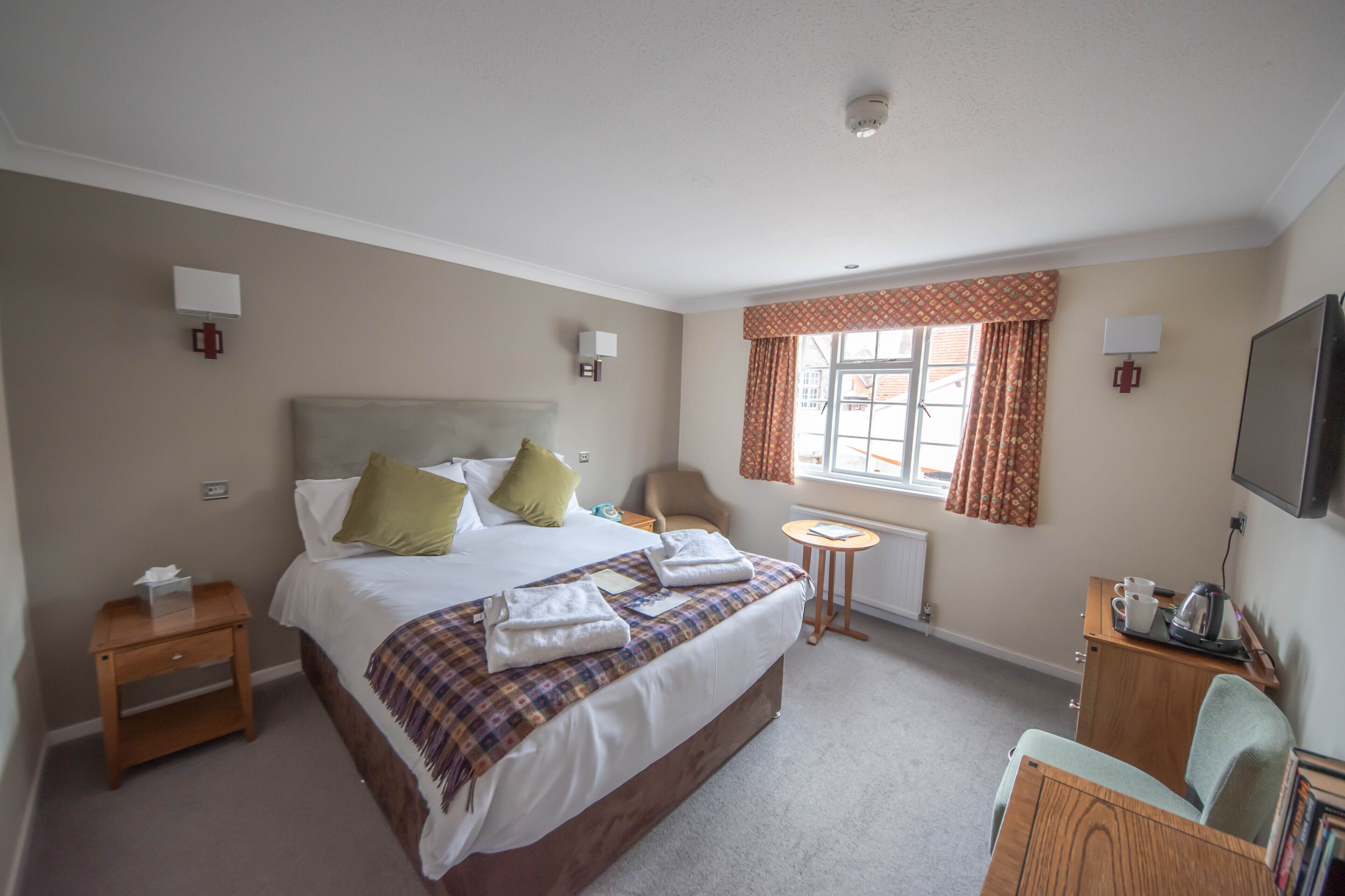 A hotel room with a large bed, a chair, a small table, and a TV.