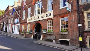 Un edificio de ladrillo tradicional con un cartel que dice "NORFOLK ARMS" y varias banderas.