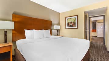 Una camera d'albergo con un letto grande, una testiera in legno, un comodino, una lampada e un quadro incorniciato appeso al muro.