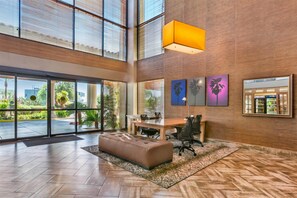 Un vestíbulo amplio con un área de descanso grande, una mesa de recepción y obras de arte en las paredes.