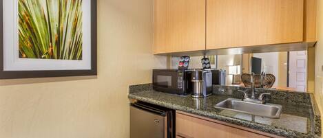 A compact kitchen with a microwave, coffee maker, and sink.