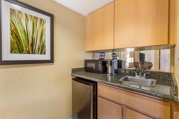 A compact kitchen with a microwave, coffee maker, and sink.